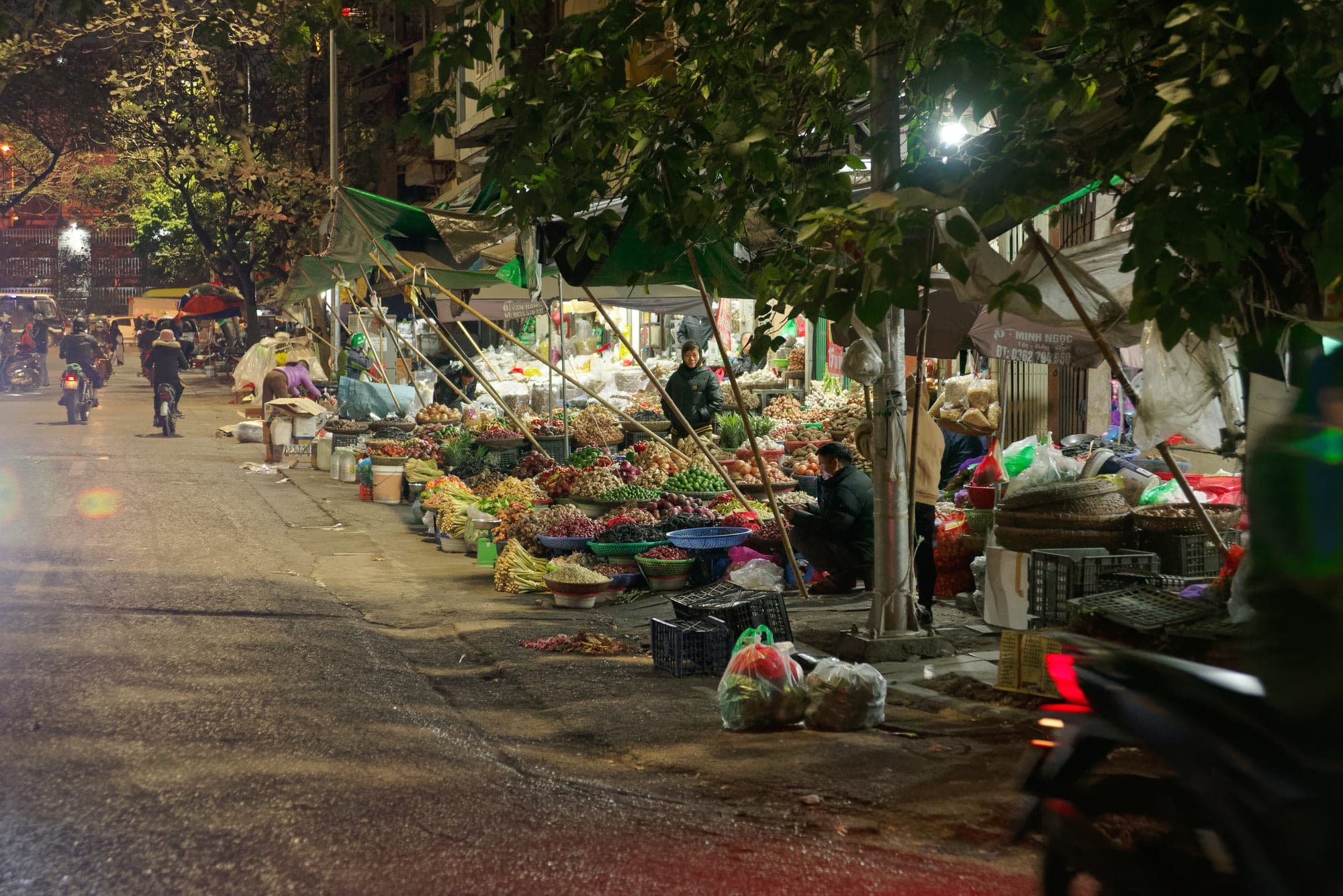 Street market in Hanoi's Old Quarter with vendors and motorbikes